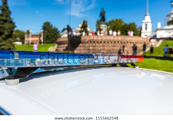 Flashing light on a police car in a city\
interior near a\
monument