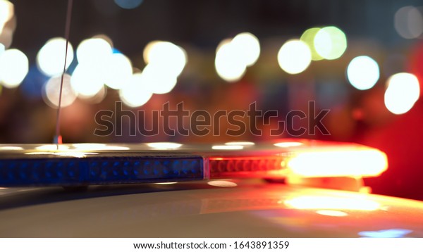 Flashing lights of a police flasher on the roof of\
a police car at night