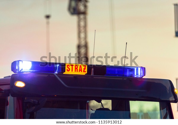 Flashing lights of red fire truck in Poland (Straz)\
at dusk