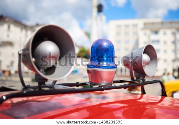 Flashing lights and sirens on the roof of an old police\
car 