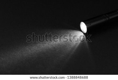 Flashlight and beam of light on a dark background