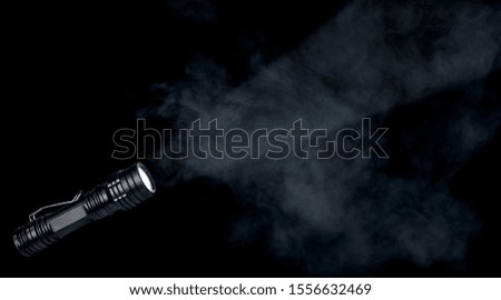 Flashlight with a light beam on dark smoke background