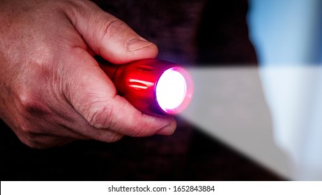 A Flashlight In A Man's Hand Illuminates A Dark Room