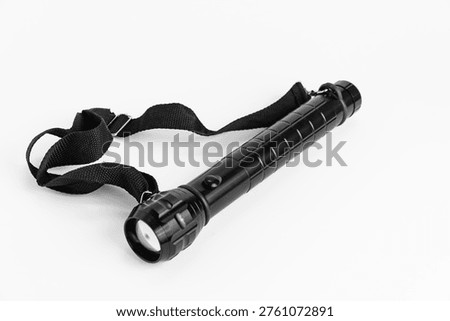 A flashlight rests on a plain surface. It is designed for photographers who need extra light during nighttime shoots in various outdoor settings.