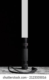 Flashlight Stands On A Table With A Narrow Beam Of Light Upwards On A Black Background.