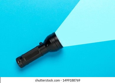 Flashlight or torch lighting up blue background - minimal concept for internet search or direction finding