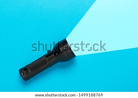 Flashlight or torch lighting up blue background - minimal concept for internet search or direction finding