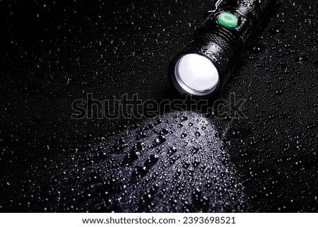 Flashlight water resistant in drops on black background.