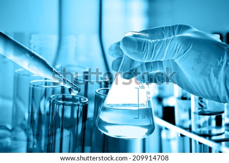 Flask in scientist hand with dropping liquid to test tube