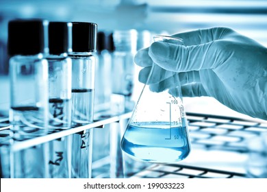 Flask in scientist hand with test tube in rack - Powered by Shutterstock