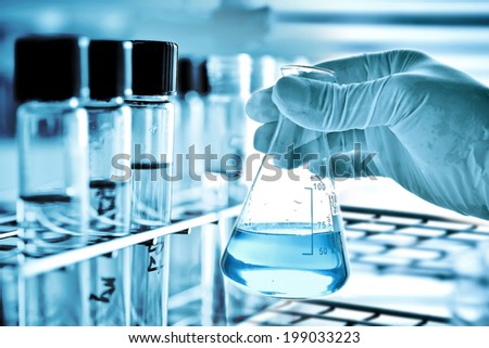 Flask in scientist hand with test tube in rack