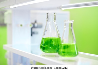 Flasks With Green Liquid On The Background Of The Chemical Laboratory