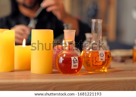 Flasks with potion and candles on table in alchemist's laboratory