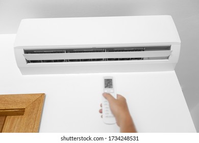 Flat Klimaanlage an der weißen Wand im Zimmer. Mann drückt den Knopf an der Ferne. Einstelltemperatur