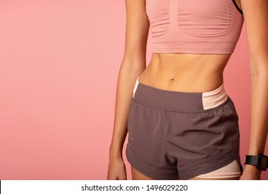 Flat Belly Exercises. Unrecognizable Woman Showing Perfect Abs Over Pink Studio Background. Cropped, Free Space