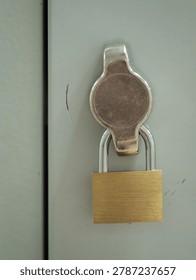 Flat brass padlock on a locker door.