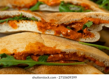 Flat breads stuffed with a roasted red pepper and walnut spread and fresh green leaves
