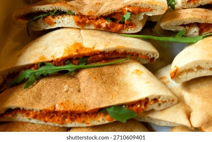 Flat breads stuffed with a roasted red pepper and walnut spread and fresh green leaves
