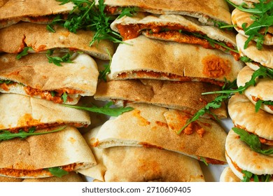 Flat breads stuffed with a roasted red pepper and walnut spread and fresh green leaves
