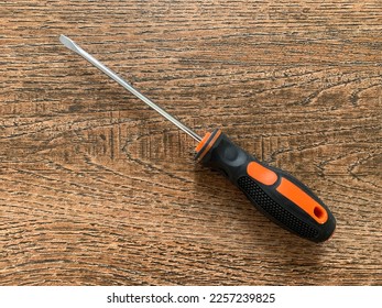 A flat head screwdriver on a wood background