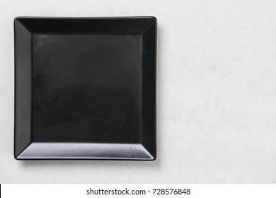 Flat Lay Above Black Square Plate On The White Marble Table Background.