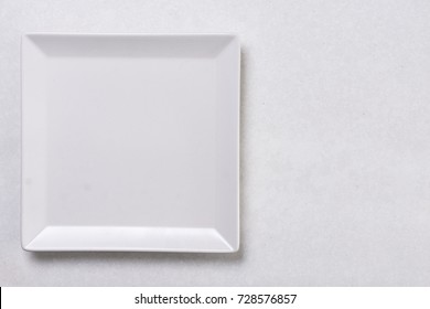 Flat Lay Above White Square Plate On The White Marble Background Table.