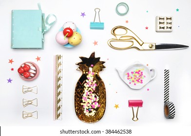 Flat lay. Accessories on the table, woman desk top. View top table, background mock up. Gold stationery,gold pineapple, mint box, colorful confettis, tea and strawberry. - Shutterstock ID 384462538