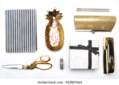 Flat lay. Accessories on the table, woman desk top. View top table, background mock up. Gold stationery,gold pineapple, handbag, notebook, pencil.Black and white