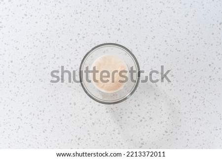 Flat lay. Activating dry yeast in a glass mixing bowl to bake naan dippers.