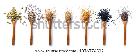 Flat lay of arranged wooden spoons with various healthy seeds in mix on white background.