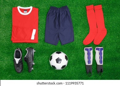 A Flat Lay Arrangement Of Football Or Soccer Kit On Grass, With Shirt, Shorts,socks, Boots, Shin Pads And Ball.