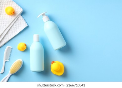 Flat Lay Baby Shampoo, Shower Gel, Hair Comb, Body Brush, Towel, Yellow Ducks On Blue Table. Top View Baby Bathing Items.