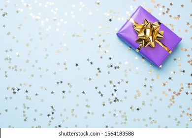 Flat Lay Background For Celebration Christmas And New Year. Gift Boxes Are Purple And Turquoise With Gold Ribbons Bows And Confetti Stars On A Blue Background. Top View Copy Space