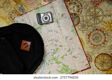Flat lay of backpack, map and camera representing travel planning and exploration.