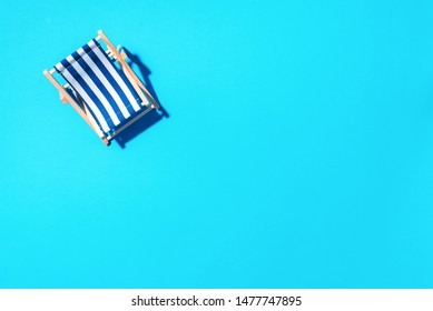 Flat Lay Of Beach Deck Chair On Blue Background With Copy Space. Summer And Travel Concept. Creative Banner