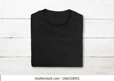 Flat Lay Of Black Folded Tshirt On Vintage White Wooden Background