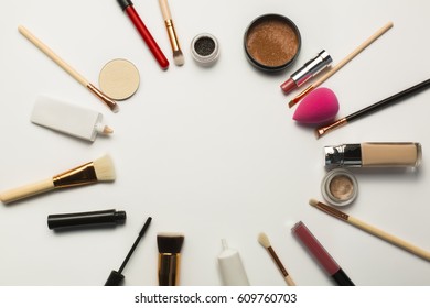 Flat Lay Of Black Mascara,makeup Brushes And Bronzer Over A White Background