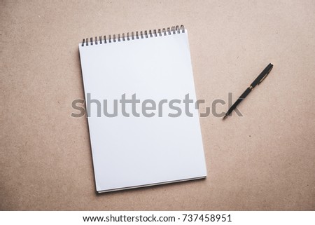 Flat lay, a blank notebook and pen on work desk, top view.