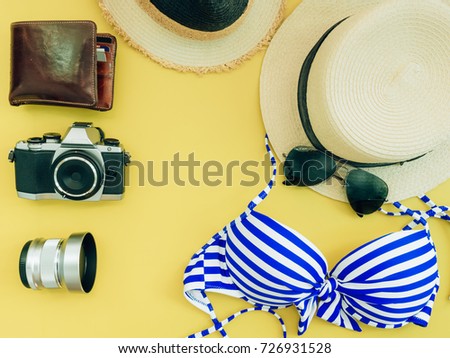 flat lay for blue bikini girl summer cloth and accessories concept with yellow background , camera and wallet