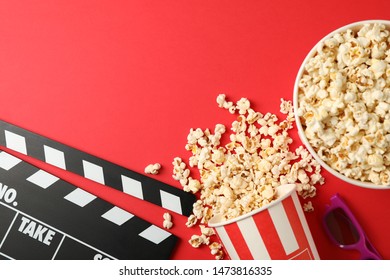 Flat lay. Buckets with popcorn, 3d glasses and clapperboard on red background