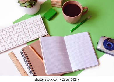 Flat Lay Business Background. White Computer Keyboard, Open Paper Notebook, Pen, Pencil, Wooden Ruler, Camera And Cup Of Coffee