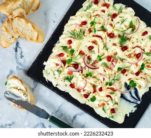 Flat lay of a butter board topped with red onions, pomegranate seeds and garnished with dill leaves and micro green. Table top view - Shutterstock ID 2226232423