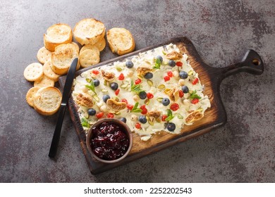 Flat lay of a butter board topped dried cherries and figs, pistachios, hazelnuts, fresh blueberries and mint served with toasts and crackers close-up on the table. Horizontal top view from above - Shutterstock ID 2252202543