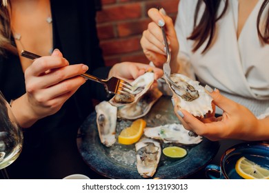 Flat Lay Of Caucasian Hands Holding Oysters With Other Seafood Dishes On A Dark Table.