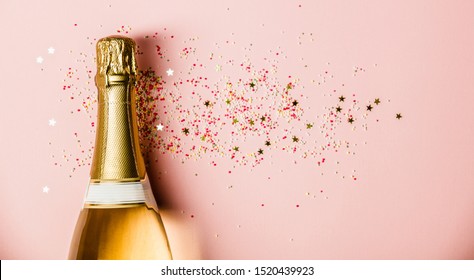 Flat lay of Celebration. Champagne bottle with sprinkles on pink background. Stockfoto