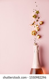 Flat lay of Celebration. Champagne bottle and golden decoration on pink background Stockfotó