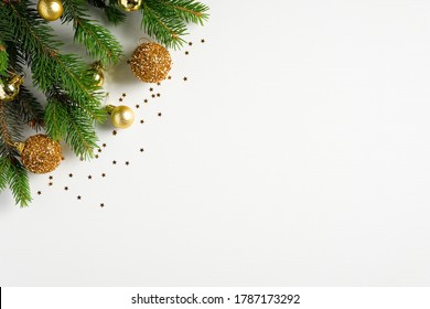 Flat lay Christmas composition. Christmas tree branch decorated golden balls and confetti on white background. Top view with copy space. Xmas banner mockup, New Year greeting card template