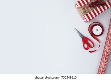 flat lay with christmas present, wrapping paper, ribbon and scissors isolated on white tabletop