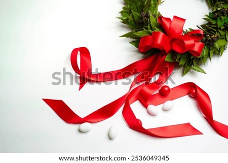Flat lay of the classical laurel wreath, which is used to celebrate university graduation in italy, with a ribbon branching out. Some confectionary is layed on the table.