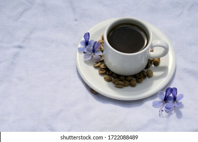 Flat lay Coffee composition  with  white cup  and beans of coffe and blue flower  on  linen tableclothtable as background